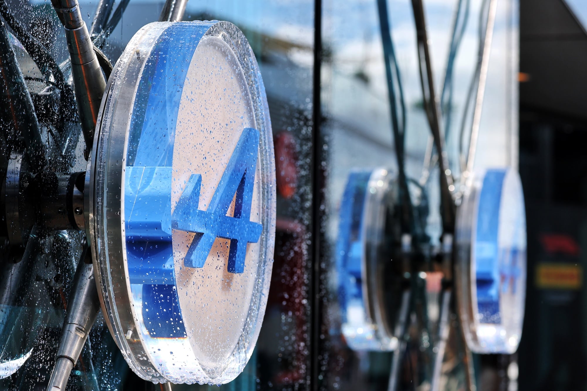 Alpine F1 Team logo covered in raindrops on the motorhome in the paddock.
