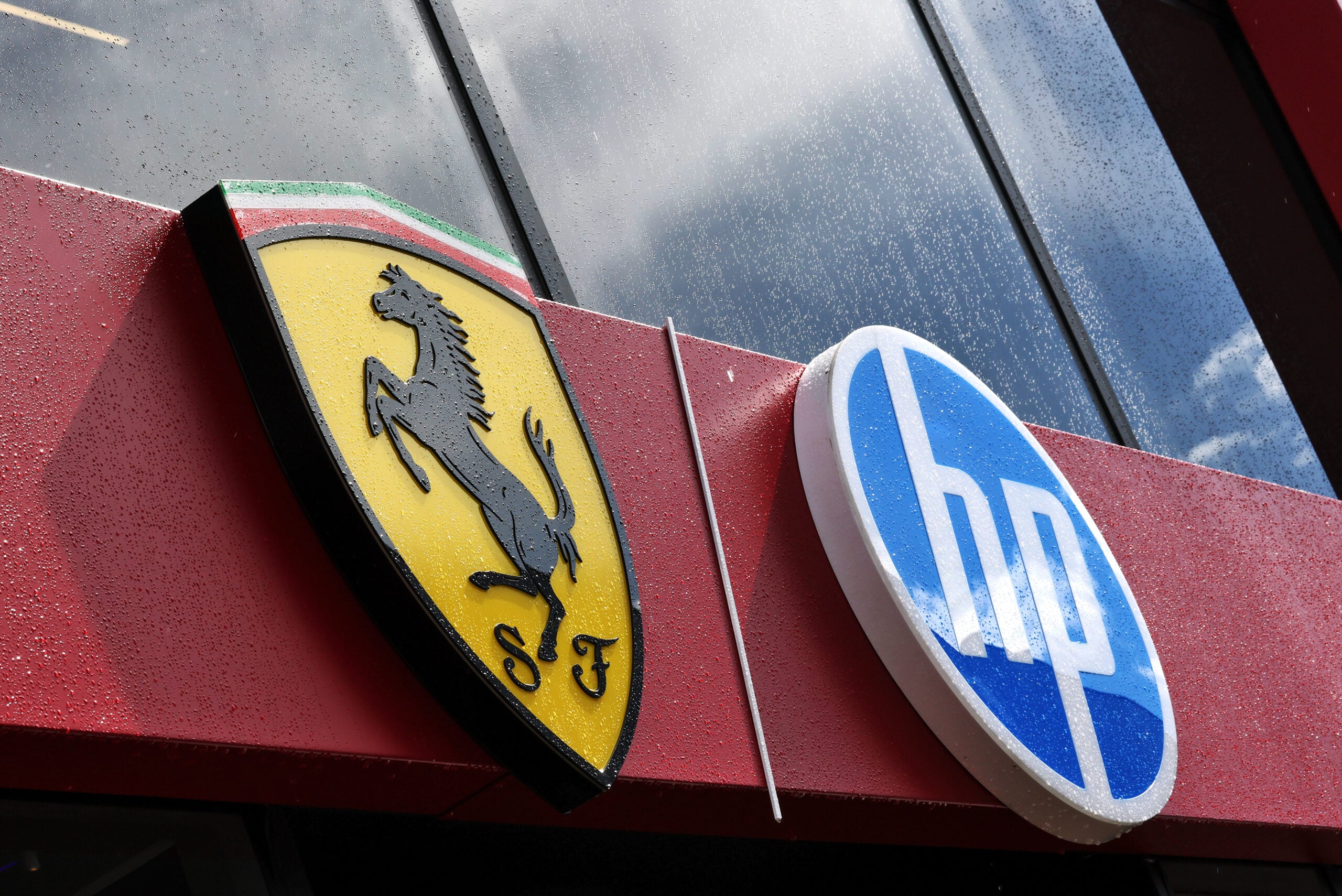 Ferrari and HP logo covered in raindrops on the motorhome in the paddock.