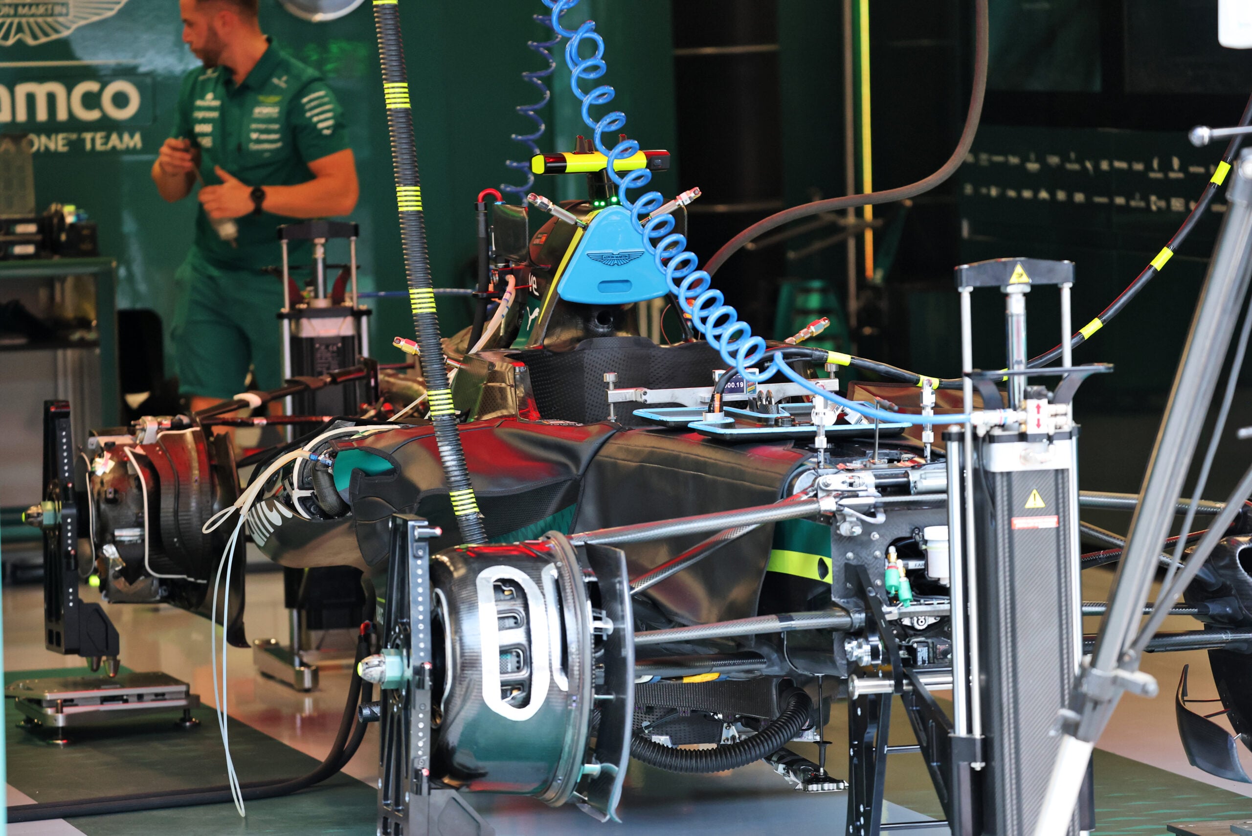 F1 hoje: Verstappen mantém suspense e Aston Martin revela carro Aston Martin F1 Team AMR26 being prepared by mechanics in the pit garage.
