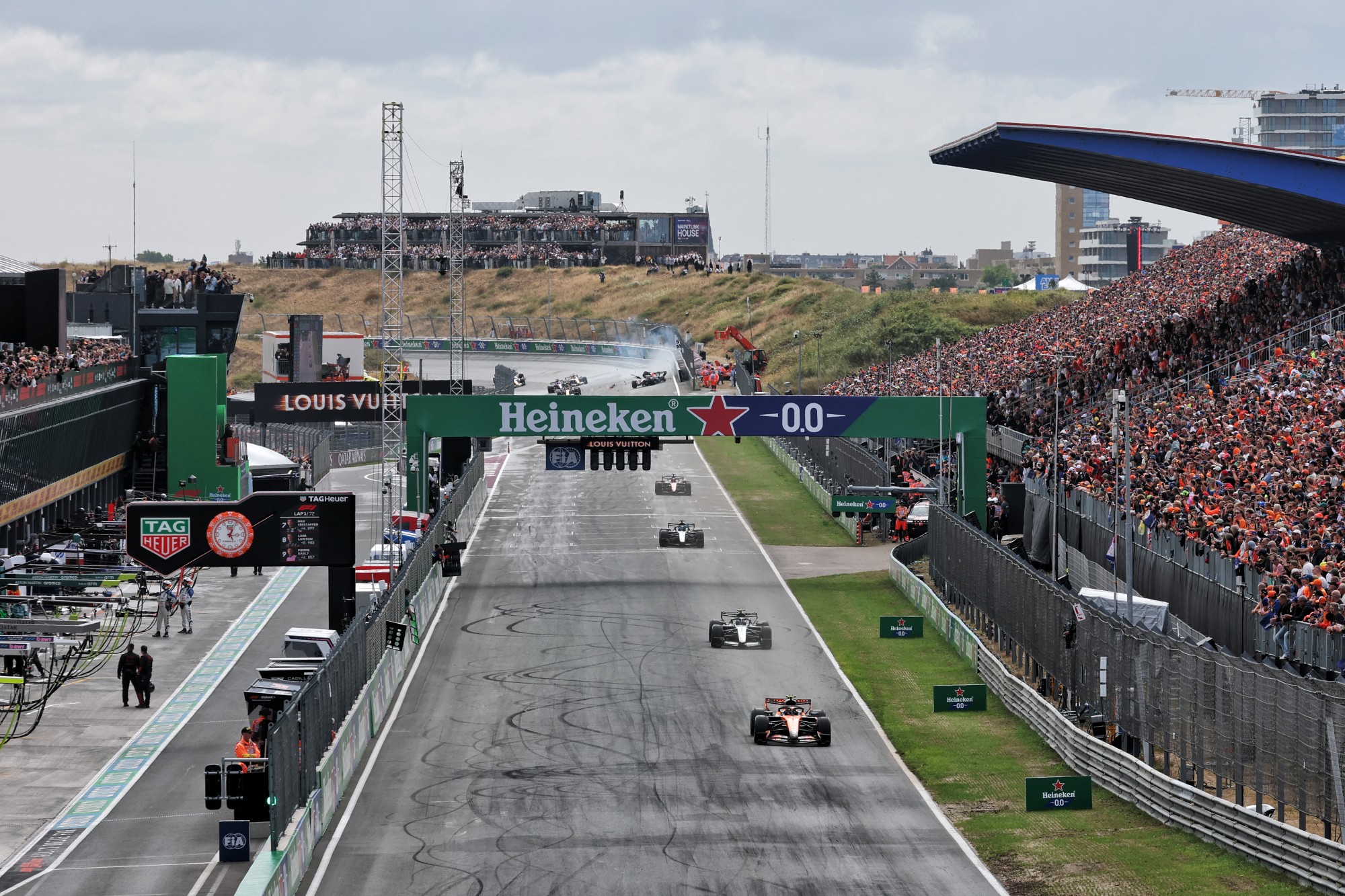 Lando Norris (GBR) McLaren F1 Team MCL40 leads as Max Verstappen (NLD) Red Bull Racing RB22 crashes in the background.